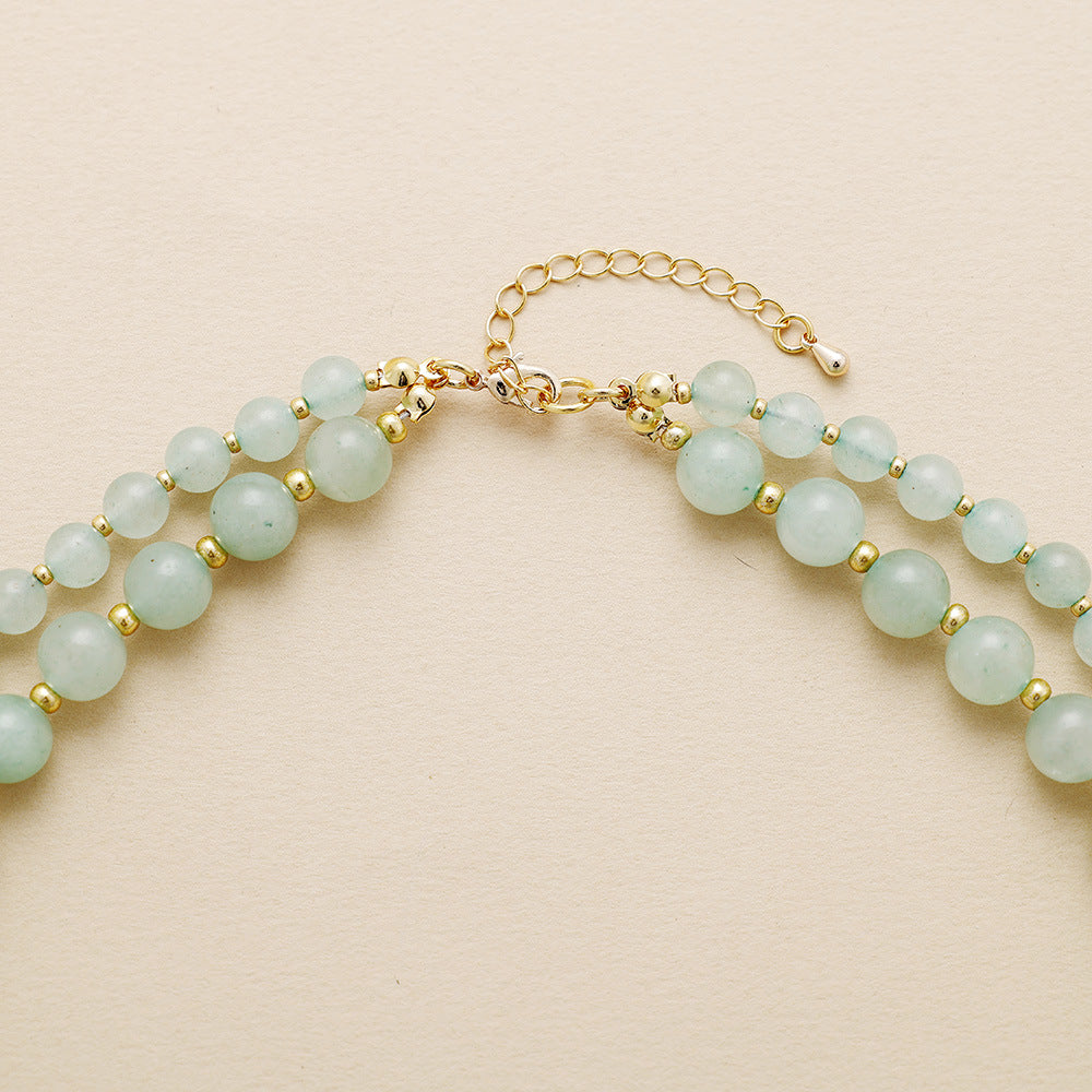 Necklace with light blue beads and gold accents on a beige background