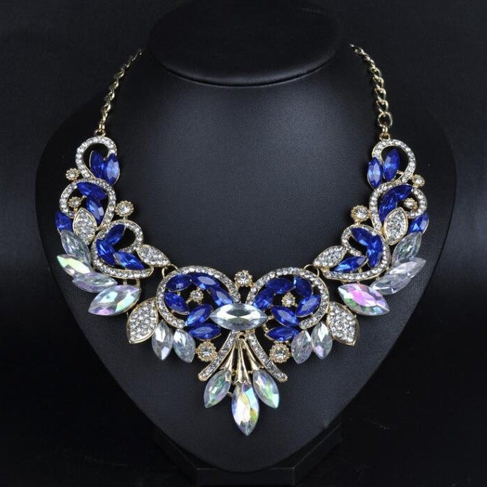 Elegant necklace with blue and clear gemstones on a black stand