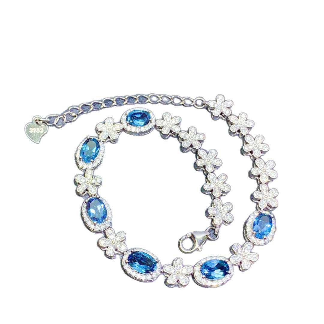 Bracelet with blue gemstones and floral designs on a white background