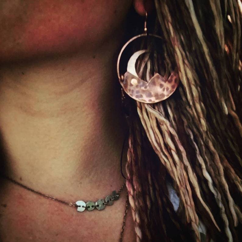 Close-up of a person wearing a necklace with a moon-shaped pendant.