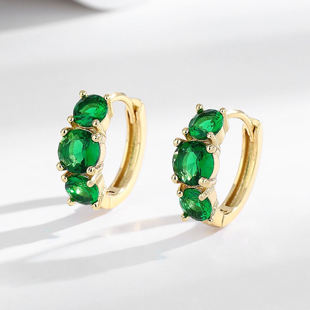 Gold hoop earrings with green gemstones on a white background