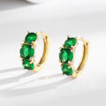 Gold hoop earrings with green gemstones on a white background
