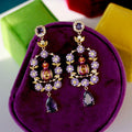 Ornate earrings with purple stones on a purple cushion