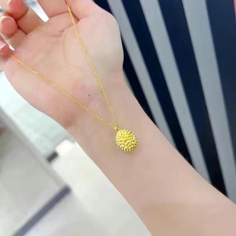Gold necklace with a unique pendant on a hand against a blurred background