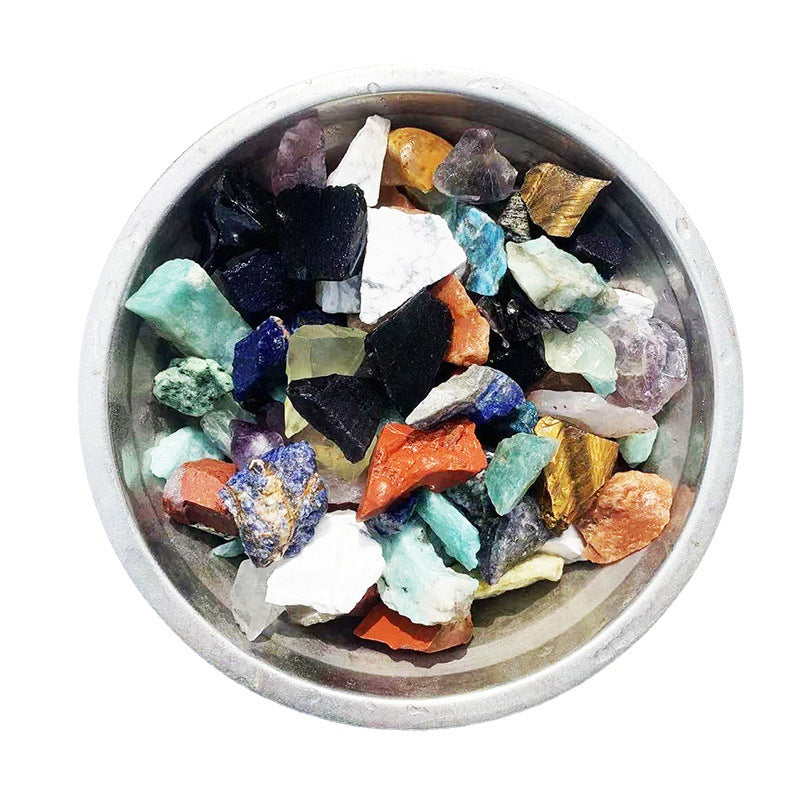 Assorted colorful crystals in a metal bowl on a white background