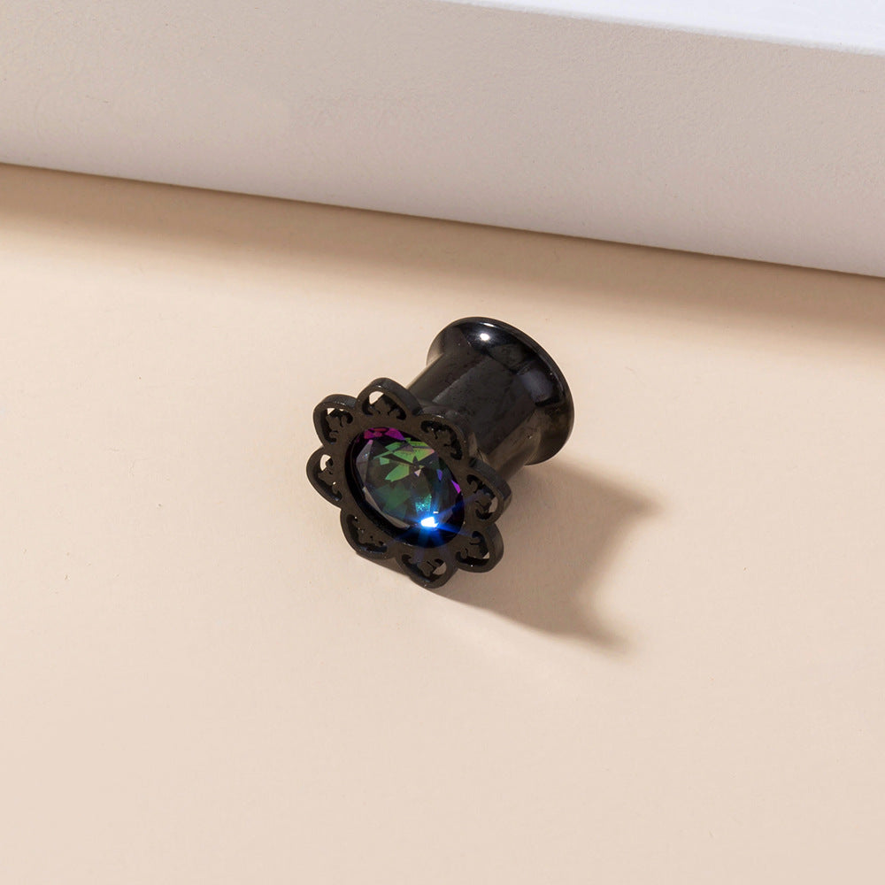 Black decorative plug with a colorful gemstone on a beige surface