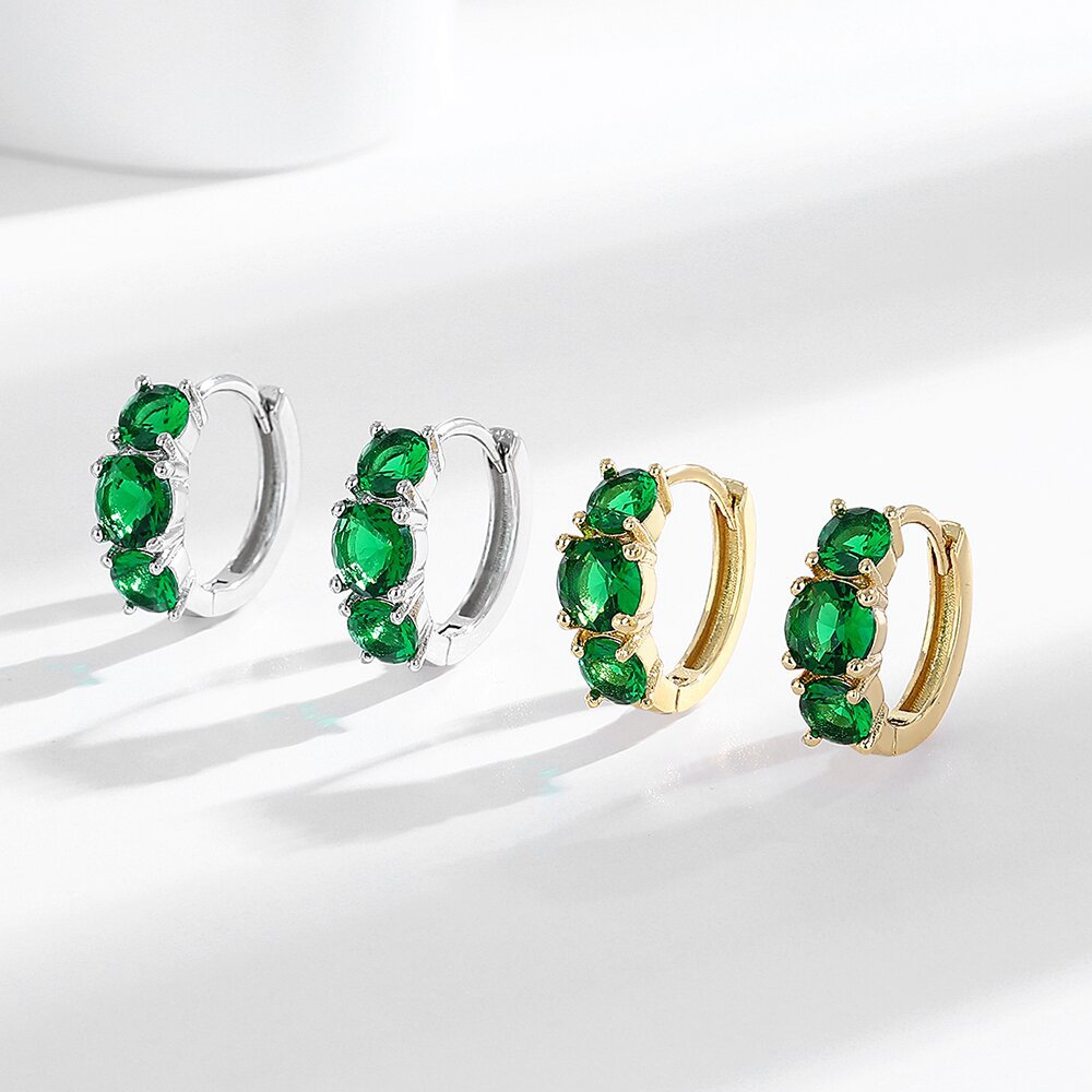 Two pairs of hoop earrings with green gemstones on a white background