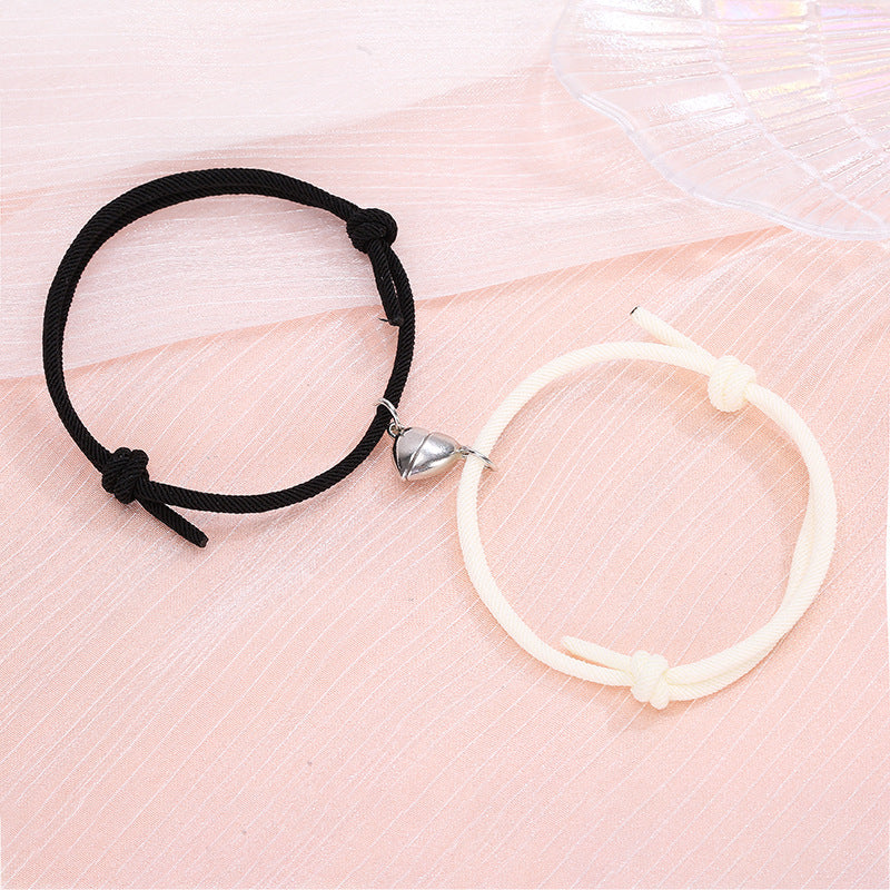Black hair tie and white hoop earring on a pink fabric background