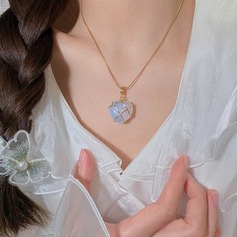 Necklace with a colorful pendant worn by a person in a white outfit.