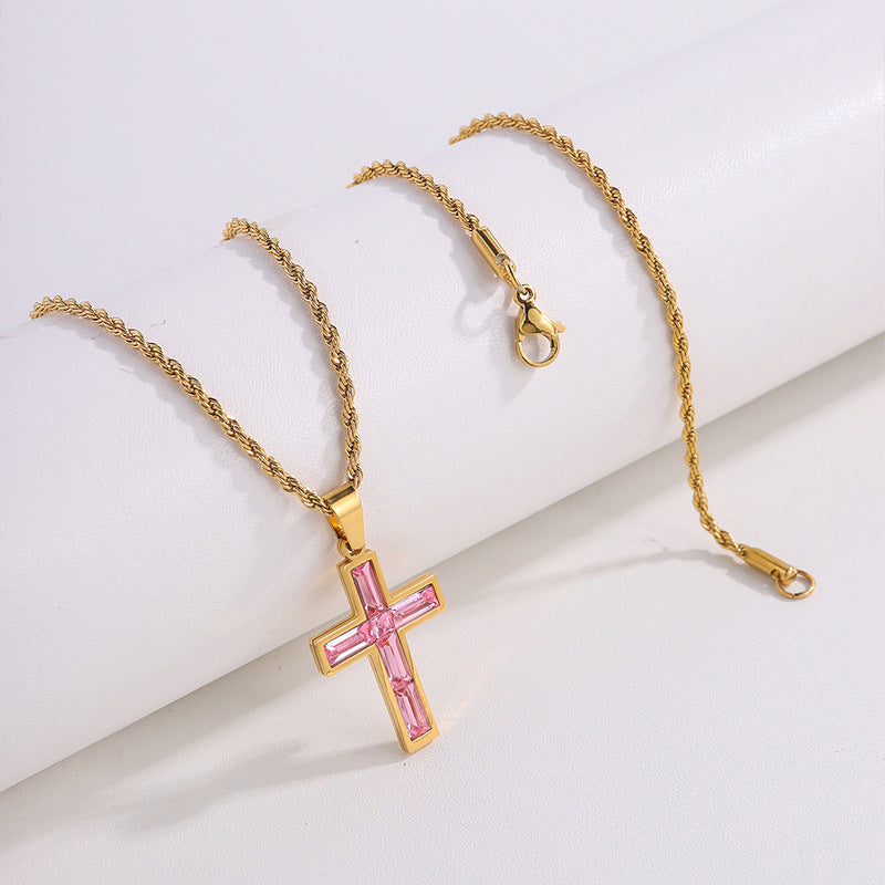 Gold necklace with a pink cross pendant on a white background