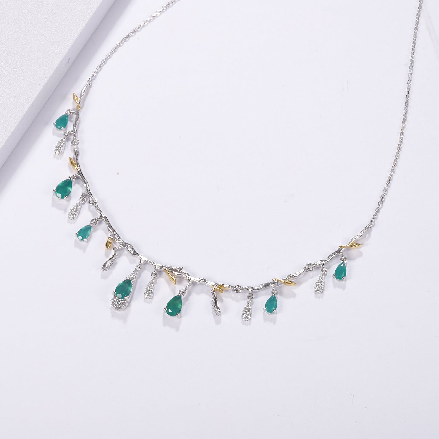 Necklace with green gemstones and gold accents on a white background