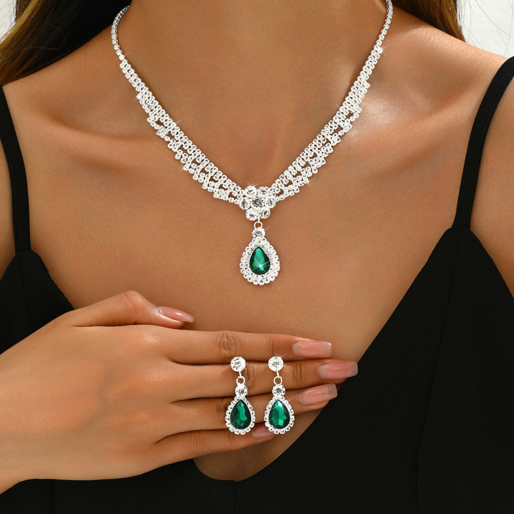 Jewelry set with necklace, earrings, and ring featuring green gemstones on a model.