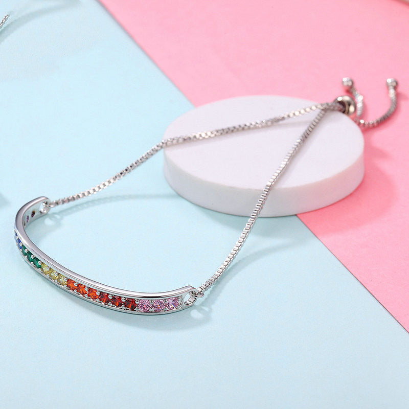 Silver bracelet with colorful stones on a pink and blue background