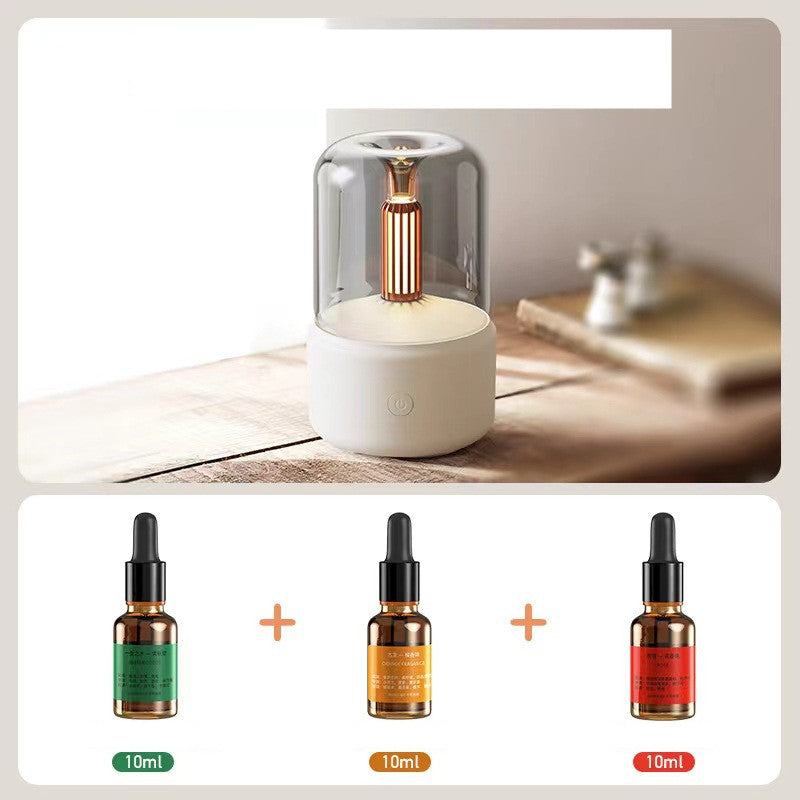 White diffuser with a glass cover on a wooden surface, accompanied by three dropper bottles of different sizes.