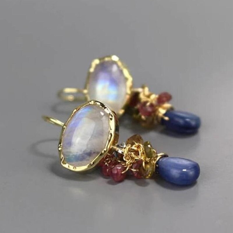 Gold earrings with gemstones on a gray background