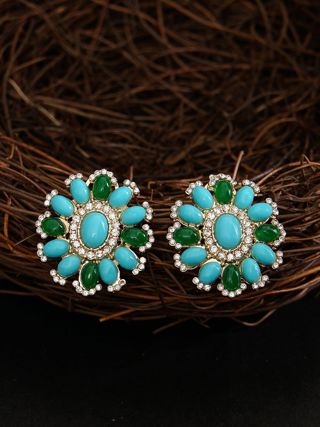 Pair of earrings with turquoise and green stones on a dark background