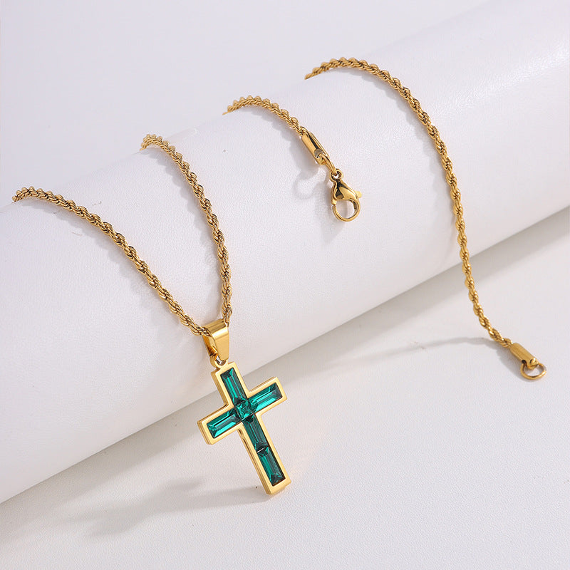 Gold necklace with a cross pendant featuring green gemstones on a white background