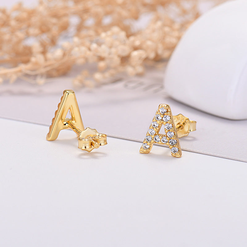 Gold letter 'A' earrings with clear stones on a light background