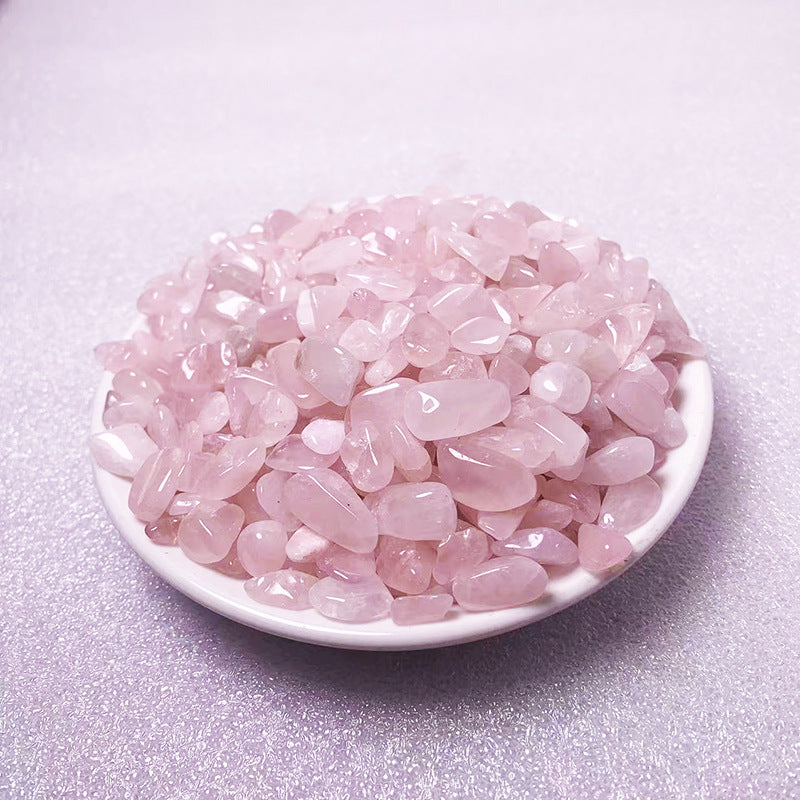 Pink crystal stones in a white bowl on a light purple background
