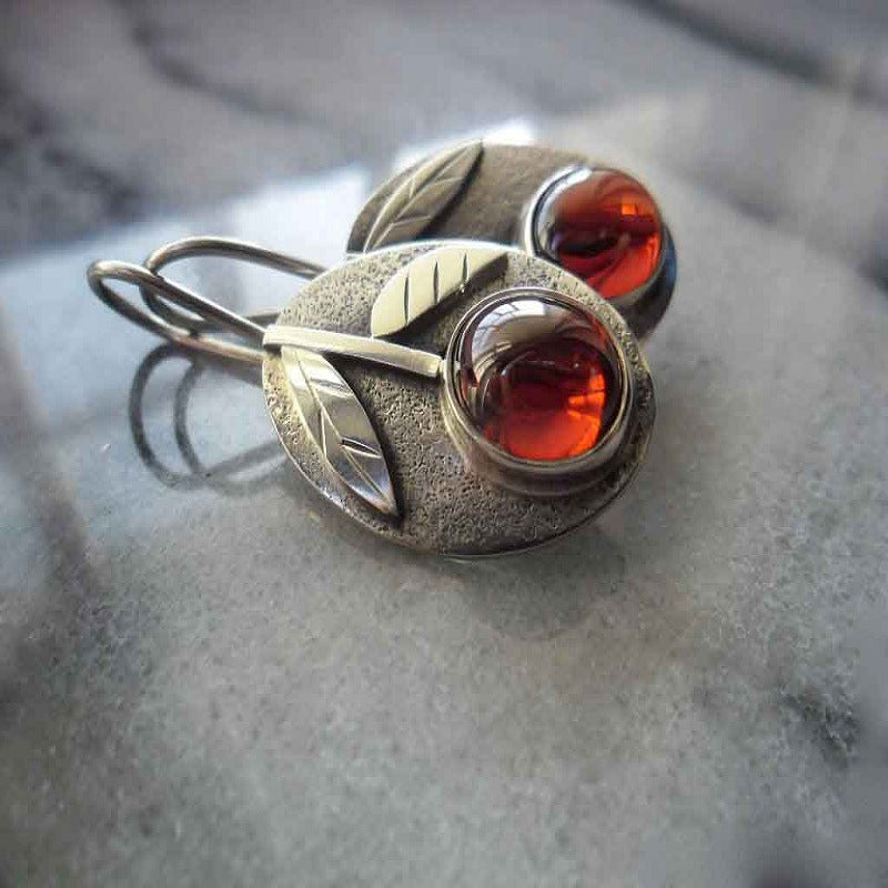 Silver earrings with red gemstones on a gray surface