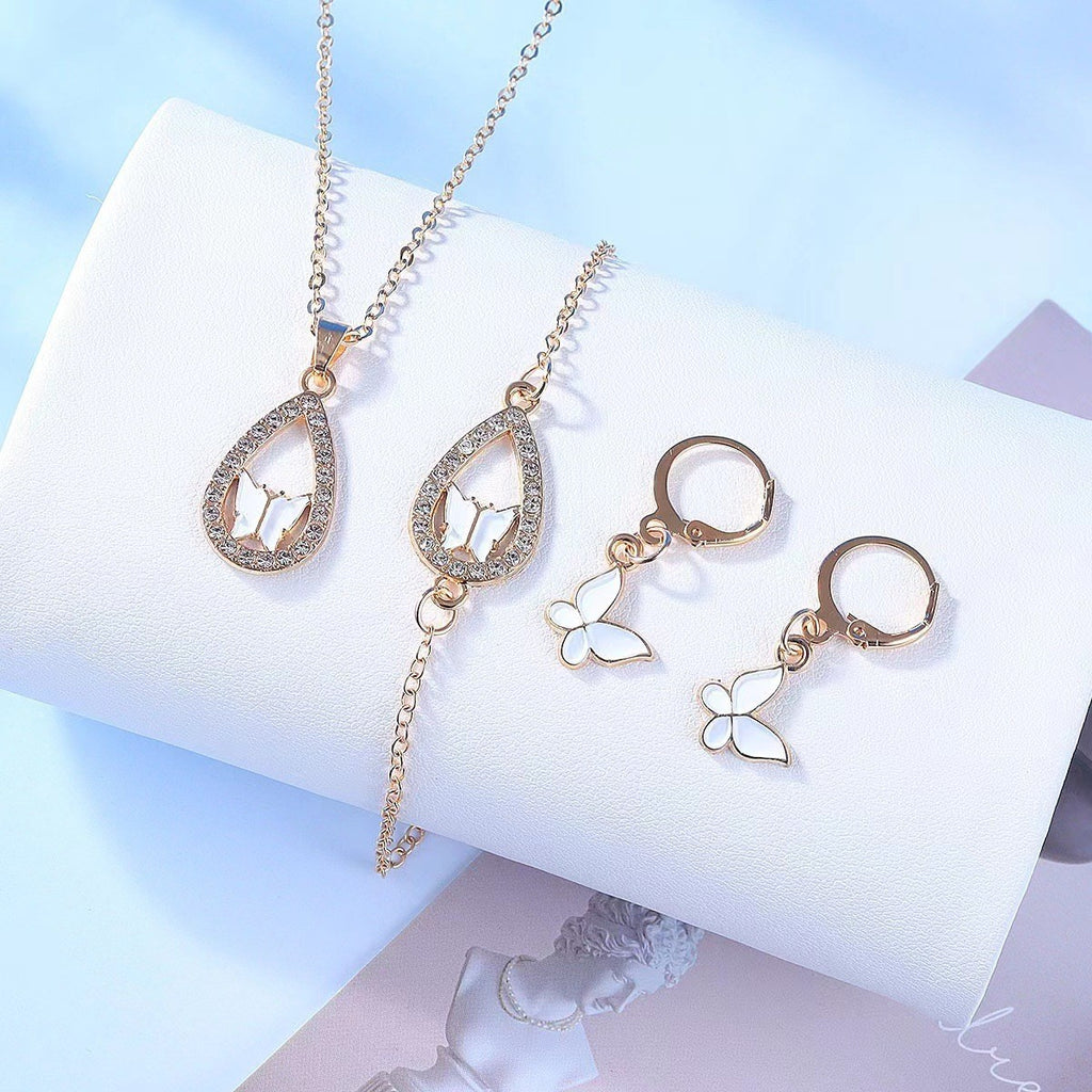 Gold jewelry set including a necklace and earrings on a white cushion with a light blue background.