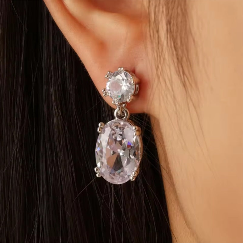 Close-up of a person wearing a sparkling earring with a clear gemstone.