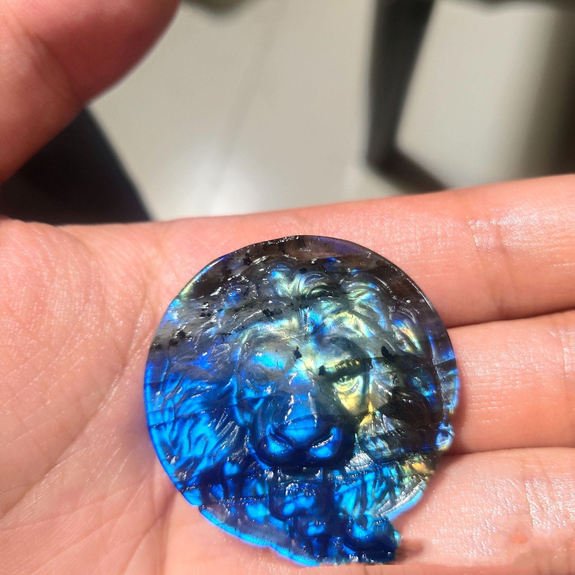 Blue glass gemstone held in a hand with a blurred background