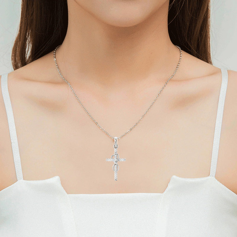 Silver necklace with a cross pendant worn by a model against a neutral background