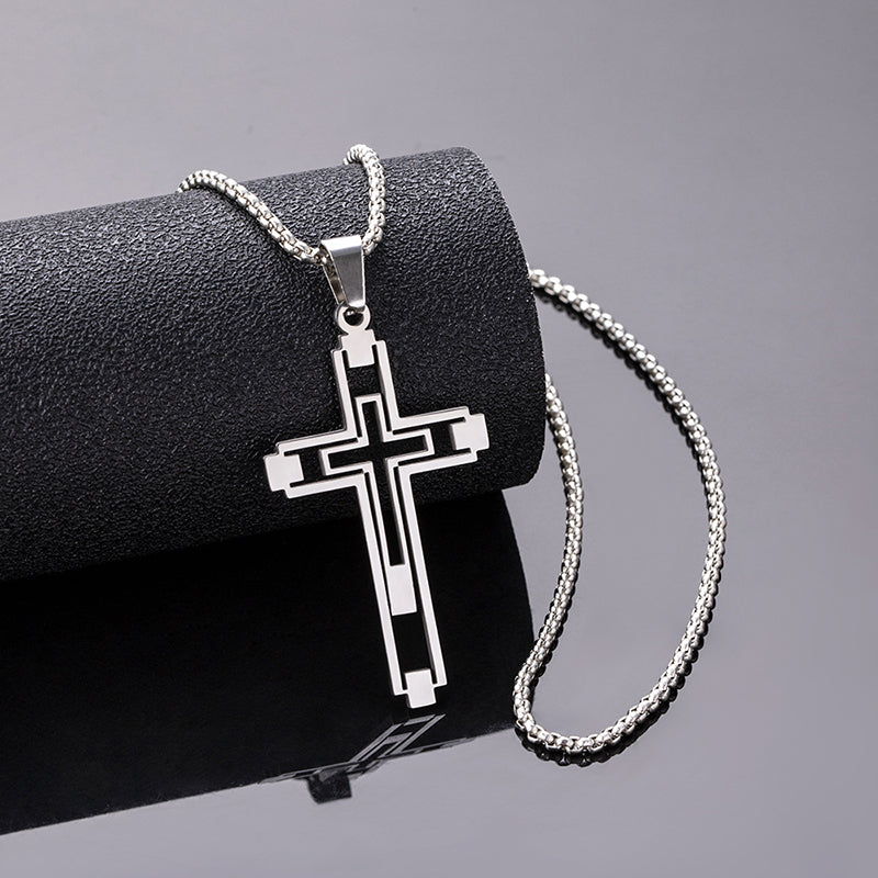 Silver cross pendant necklace on a black surface