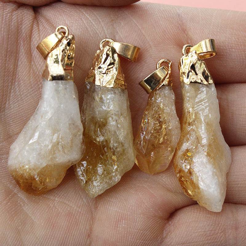 Four crystal pendants with gold tops held in a hand.