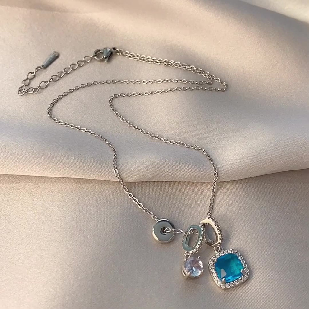 Silver necklace with blue pendant on a beige surface