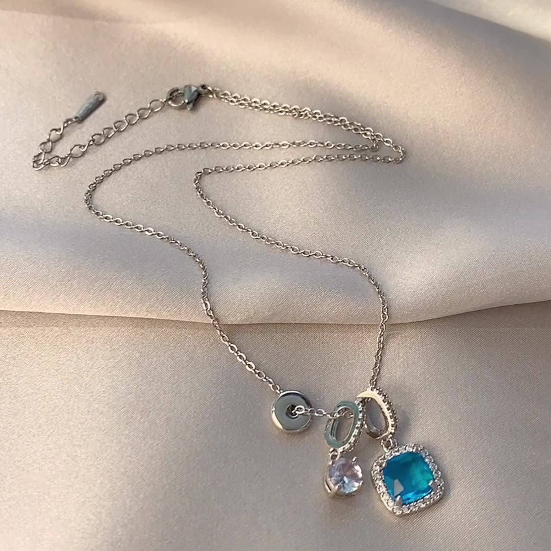 Silver necklace with blue pendant on a beige surface
