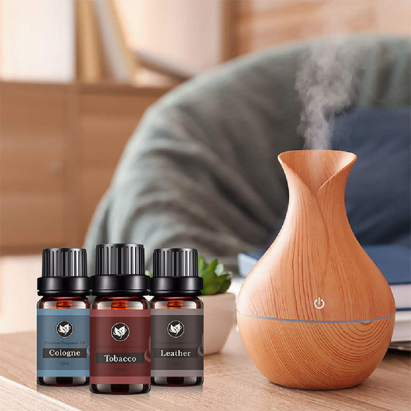 Wooden diffuser with three bottles of cologne, tobacco, and leather scents on a table.