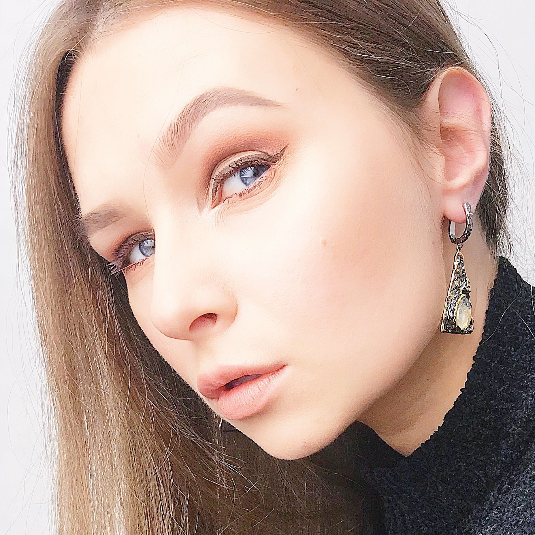 Close-up of a person wearing a unique earring with a white background