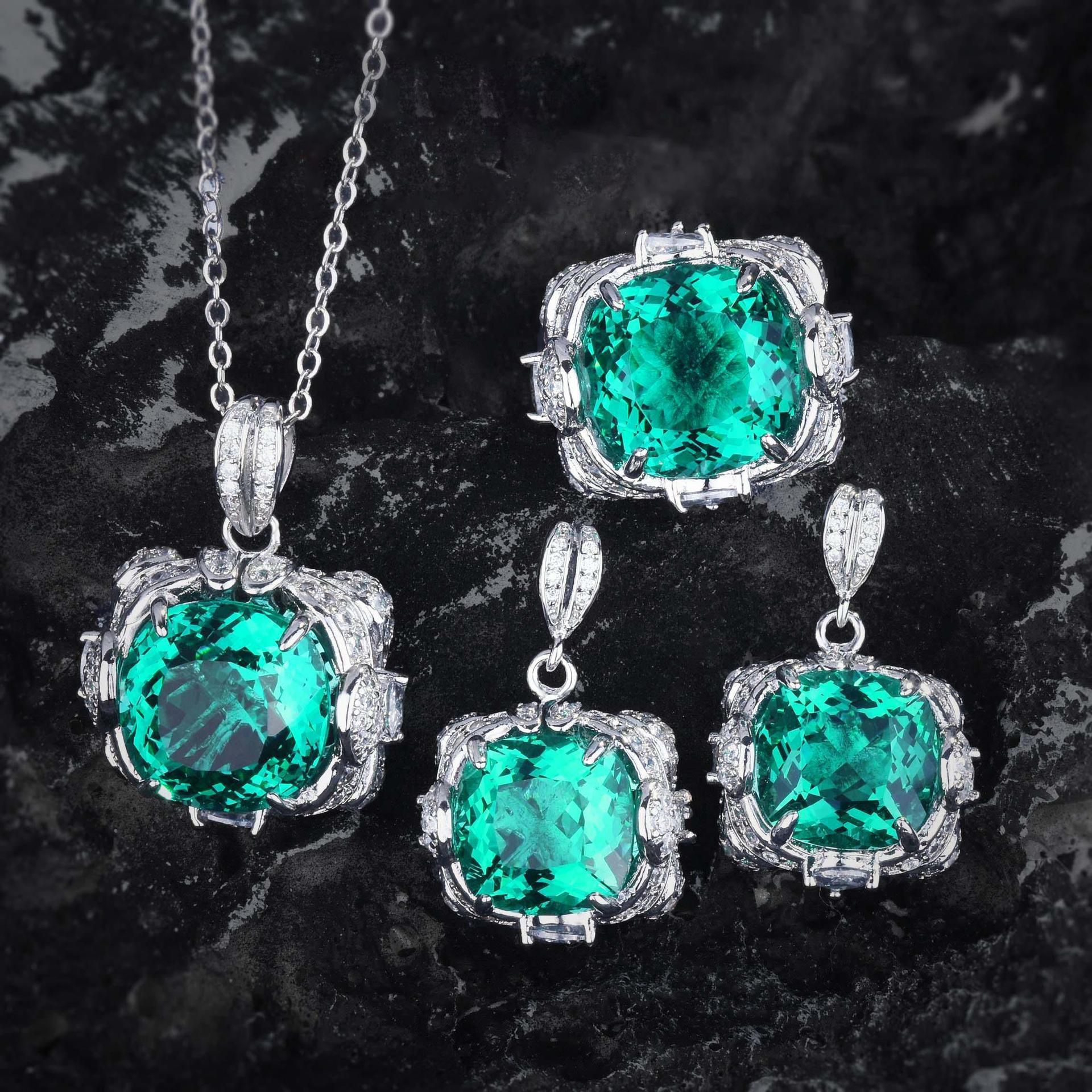 Jewelry set with emerald green gemstones on a dark marble background