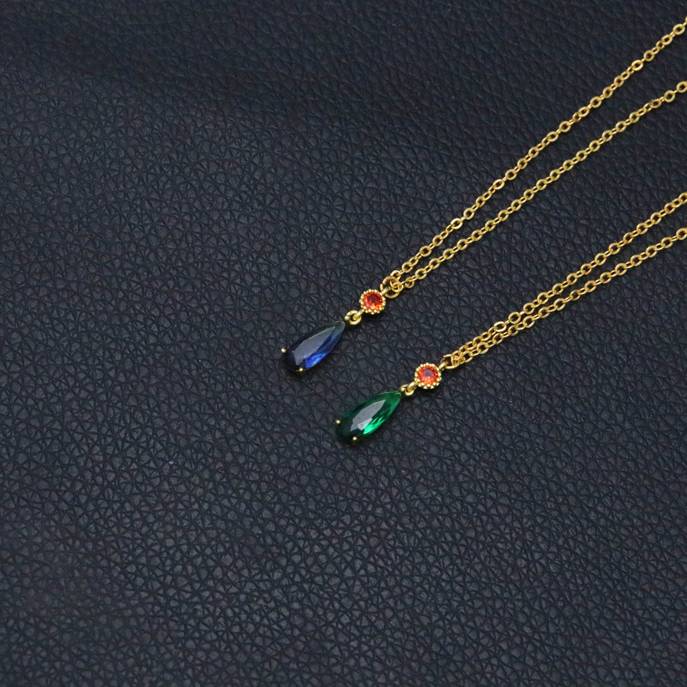 Two gold necklaces with gemstones on a dark textured surface