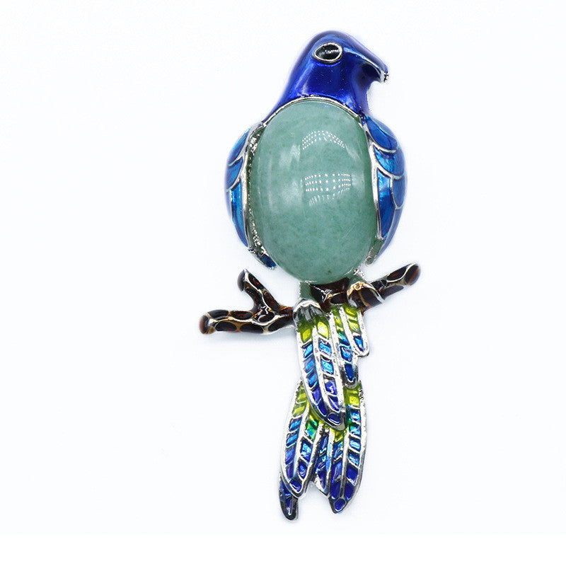 Decorative bird-shaped object with a green stone on a white background