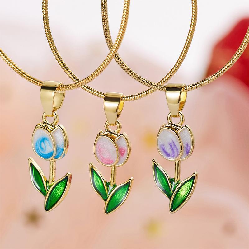 Three gold necklaces with floral pendants on a blurred background