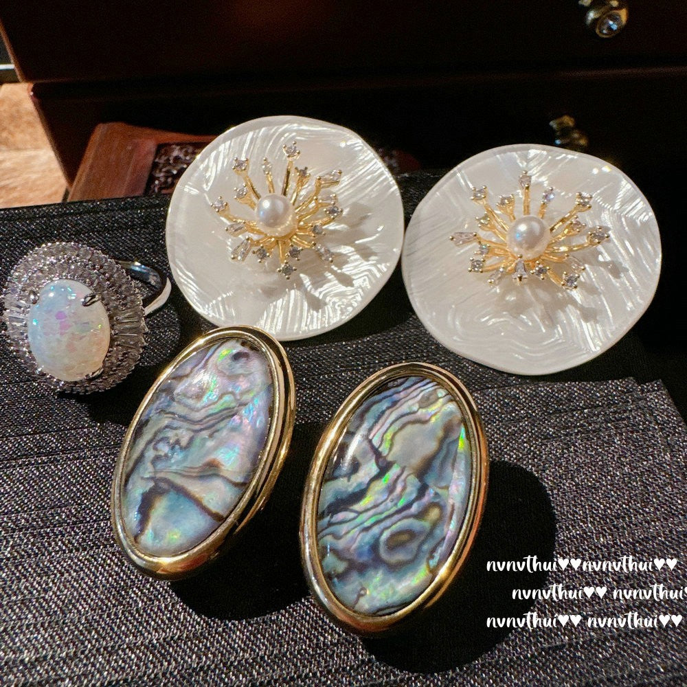 Pair of earrings with shell and pearl design on a textured surface