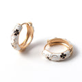 Pair of gold and white hoop earrings with floral designs on a white background