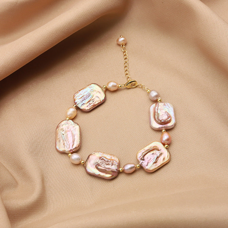 Pearl bracelet with gold chain on beige fabric