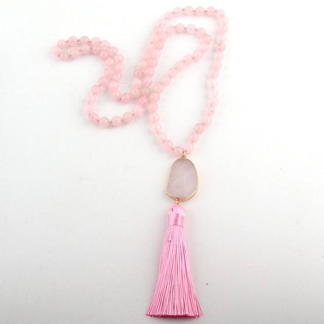 Necklace with pink beads and tassel on a light gray background
