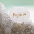White stone with 'Happiness' text on a crystal background