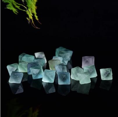 Colorful decorative stones on a reflective surface with a dark background