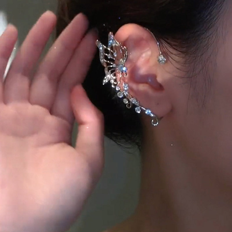 Close-up of an ear with a decorative earring being adjusted by a hand.