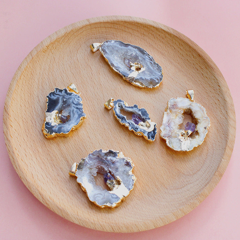 Five geode slices with gold accents on a wooden plate against a pink background