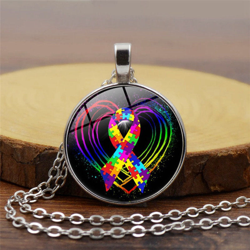 Necklace with a colorful autism awareness ribbon pendant on a wooden surface