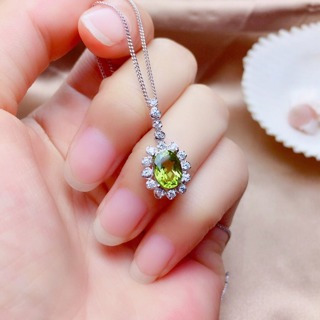 Green gemstone pendant on a chain held in a hand