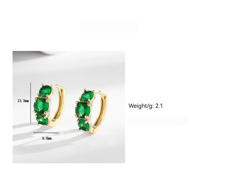 Gold hoop earrings with green gemstones on a white background