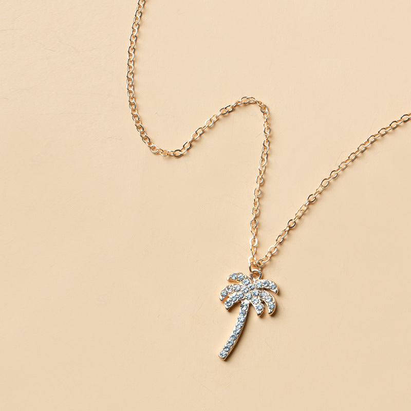 Gold necklace with a palm tree pendant on a beige background